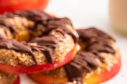 Multiple apple samoas near one another. The slices are topped with a chocolate drizzle.