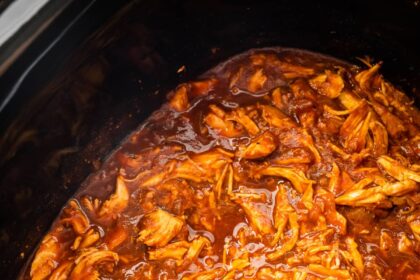 A slow cooker pot full of bbq shredded chicken.