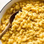 A large pot of cottage cheese mac and cheese with a wooden serving spoon.