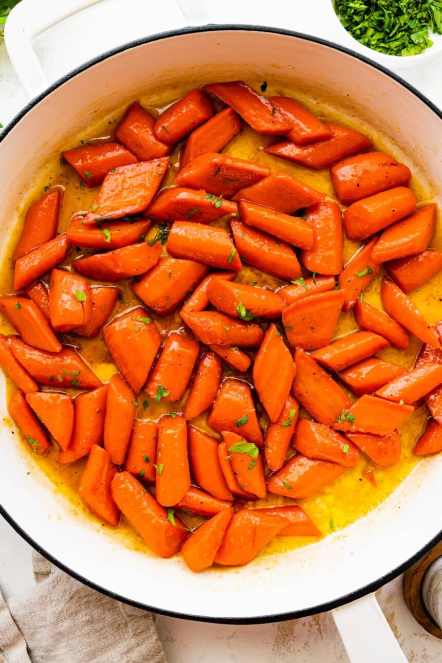 Glazed carrots cooked in a large pot and topped with fresh thyme.