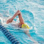 Person doing freestyle stroke in a swimming pool lane