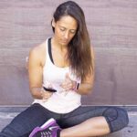 A woman sitting on the ground checking her blood sugar level