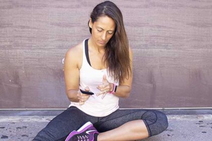 A woman sitting on the ground checking her blood sugar level