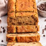 Multiple slices of coconut flour banana bread lean against one another near the loaf of bread.