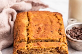 Multiple slices of coconut flour banana bread lean against one another near the loaf of bread.