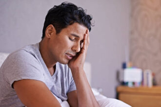 Man sitting in bed looking tired