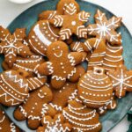 Multiple gingerbread cookies decorated with icing on a plate.