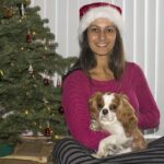 Christel sitting with dog in front of Christmas tree