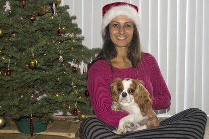 Christel sitting with dog in front of Christmas tree