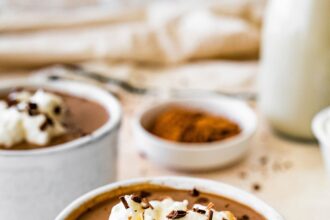 Protein hot chocolate in a white ceramic mug topped with whip cream and shaved chocolate.