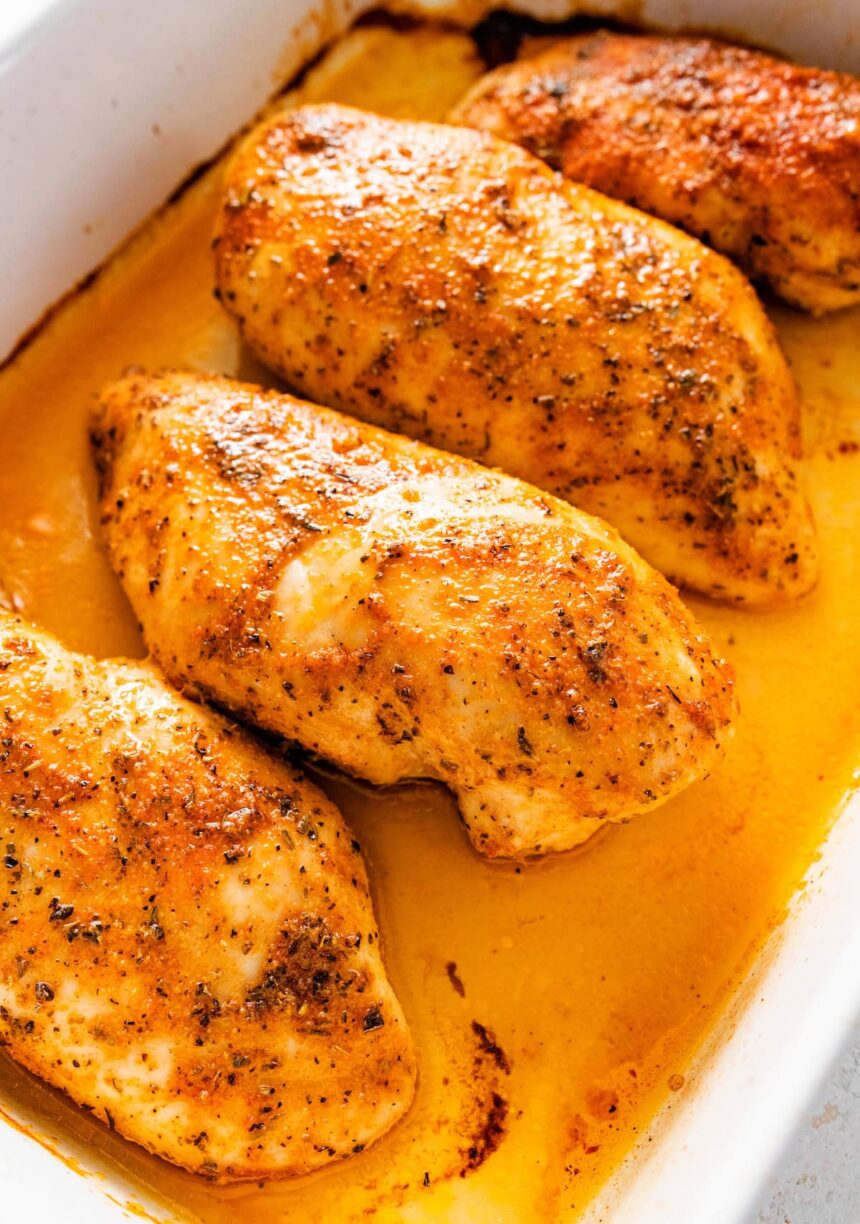 Four baked chicken breasts in a large baking dish.