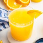 An adrenal cocktail in a glass with a clear straw in it. An orange slice is on the edge of the glass.