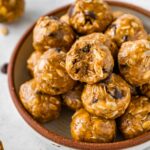 No bake energy balls piled in a bowl, with one ball showing a bite taken out of it.